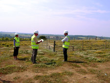 Three people wearing safety gear standing in a grassy area